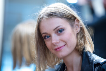 Close-up portrait of a beautiful young blonde woman smiling in a wig shop. Selective focus