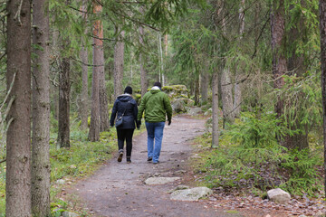 Obraz premium A man and a woman are walking along a path in the forest