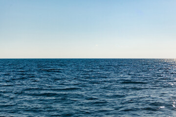 Sea skyline, top frame clear blue-gray sky, bottom of the sea frame with afforestation of the sun