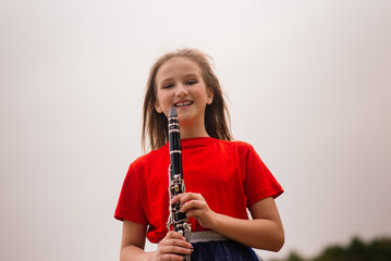 Young attractive girl playing clarinet, ebony in fall park