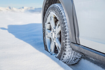 Close up of a car with winter tire on snow covered mountain road