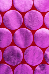 Close up red fabric with group of pink foil circles