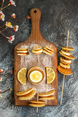 Vertical view of classic American pancakes with lemons on wooden cutting board on gray background