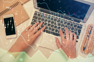 Double exposure of woman hands working on computer and forex graph hologram drawing. Top View. Financial analysis concept.