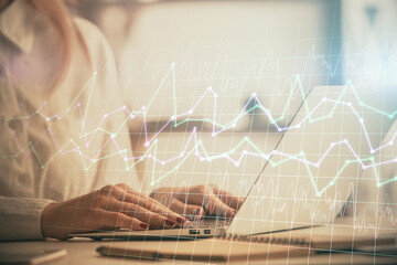 Double exposure of woman hands working on computer and forex graph hologram drawing. Financial...