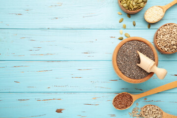Healthy superfood: sesame, pumpkin seeds, sunflower seeds, flax seeds and chia on blue. Seeds on spoon