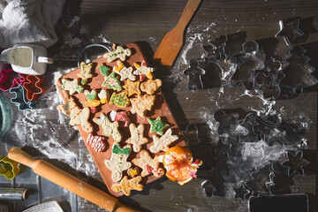 Baked ginger cookies in different shapes lie on a wooden tray. The concept of New Year's traditions and the cooking process. Cookies on a dark brown wooden table. Family production, winter holidays 