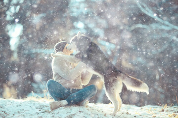 young man hugs a husky dog in the winter in the forest, a man and a dog hug together and play in a winter nature landscape