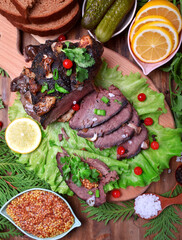 Baked elk ham sliced and topped with greenery and cranberries on the salad leaves. Served meat meal