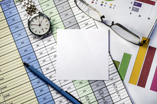 there is a blank white sheet on the business documents. near which there are glasses and a wristwatch. Business concept