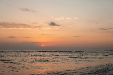 Colorful sunset on a sandy beach, waves with foam on the sand. Ocean, coast. Soft selective focus.