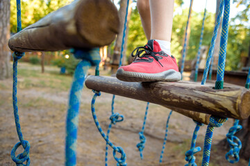 Boy foot shoe close up in adventure climbing high wire park - people on course in mountain helmet and safety equipment
