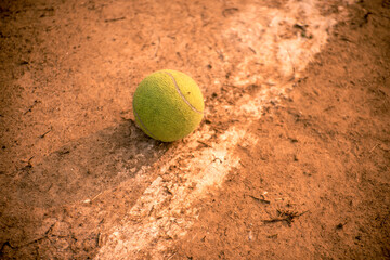 Close-up of tennis ball on clay court on the side line.