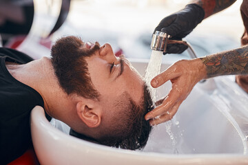 Crop barber washing hair of hipster