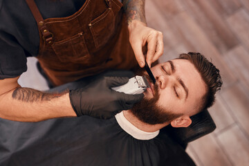 Crop barber grooming mustache of client
