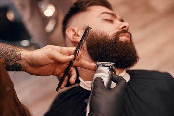 Crop barber trimming beard of dandy client