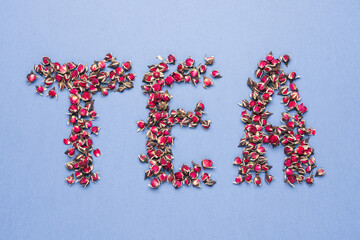 The inscription Tea made from dried rose flowers on blue background. Flower tea concept