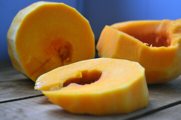 Sliced ​​orange pumpkin on a wooden board. Fresh vegetables without skin. Pieces.