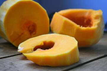 Sliced ​​orange pumpkin on a wooden board. Fresh vegetables without skin. Pieces.
