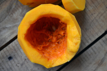 Sliced ​​orange pumpkin on a wooden board. Fresh vegetables without skin. Pieces.