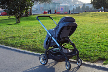 Baby stroller on the background of a green lawn in the city park lugano on a sunny day. Switzerland