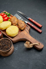Delicious cutlet meal with chopped vegetables green for dinner with pepper and ketchup on dark background
