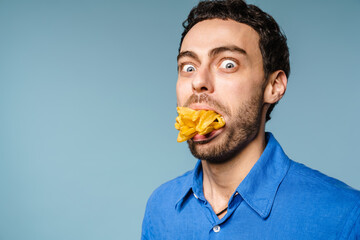 Shocked handsome guy posing with french fries in his mouth
