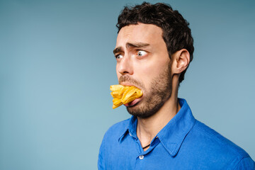 Shocked handsome guy posing with french fries in his mouth