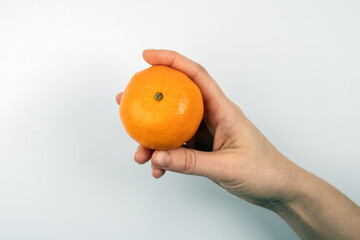 One tangerine in a woman's hand on a white background