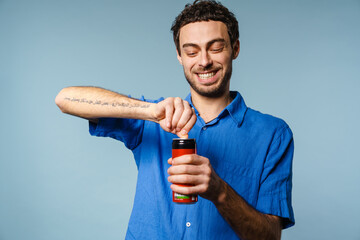 Joyful handsome guy smiling while opening soda can
