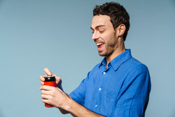 Joyful handsome guy smiling while opening soda can