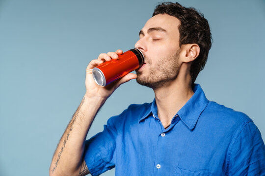 Happy handsome guy drinking soda with eyes closed