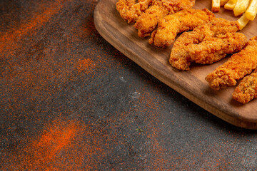 Half shot of tasty dinner with crispy fried chicken and potatoes on mixed color background