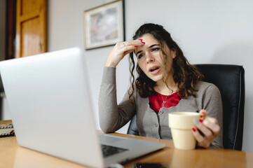 Close-up casual caucasian attractive young woman using computer working at office desk with doubtful face.