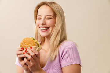 Cheerful beautiful girl laughing while posing with hamburger