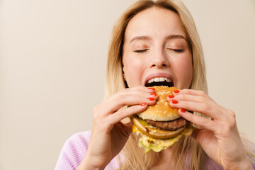 Happy beautiful hungry girl eating hamburger on camera