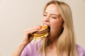 Excited beautiful hungry girl eating hamburger on camera
