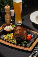 Eisbein roasted pork knuckle with potatoes and beer on the table at restaurant