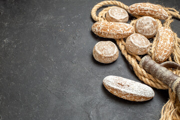Variety of delicious cookies on rope and ancient pottery on black background