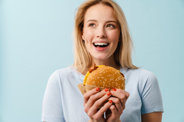 Cheerful beautiful girl smiling while posing with hamburger