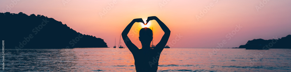 Wall mural silhouette of travel asian woman relax on sea beach in sunset at thailand