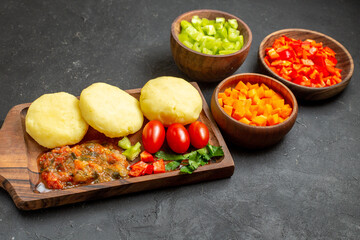 Cooking with fresh vegetables on a cutting board and chopped foods on the black table