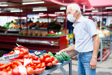 retired european man wearing medical mask protecting against virus buying tomatoes in market