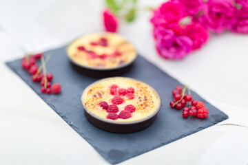 Crème brulée aux framboises et groseilles fait maison sur une ardoise noire