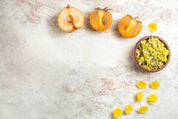 a bowl of bright yellow flowers and palms and half pear on marble background