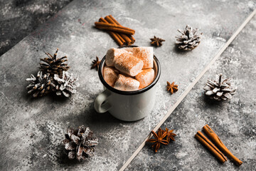 Vintage white metal cup with hot chocolate and marshmallow on the rustic background. Hygge winter evening. Selective focus. Shallow depth of field.