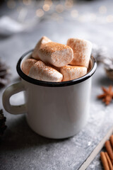 Vintage white metal cup with hot chocolate and marshmallow on the rustic background. Hygge winter evening. Selective focus. Shallow depth of field.