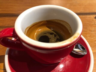 Red and White Cup of Espresso with Liquid and Spoon in Focus, High Angle