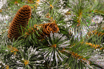 Close-up of an artificial Christmas tree with frost, snow and cones as a Christmas background