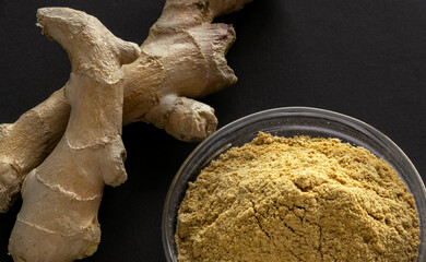 Ginger powder in bowl and ginger root
